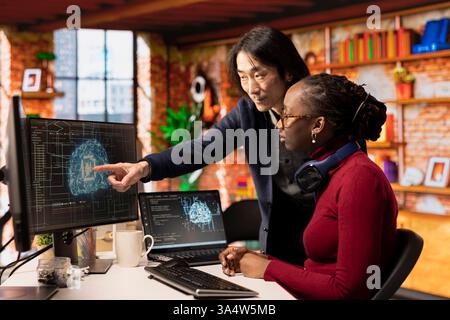 CTO supervisor in artificial intelligence focused startup overseeing worker designing, coding and debugging applications. Team leader supervising employee doing code testing and quality assurance Stock Photo