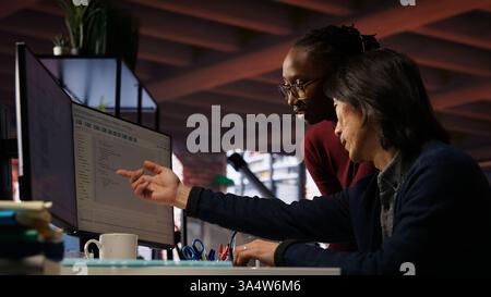 AI startup office admin asks questions to senior team leader before starting implementing machine learning. Tech venture company worker requests help from manager to fix code bugs, camera B Stock Photo