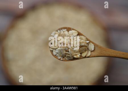 Breakfast cereals in wooden spoon. Healthy muesli with oat flakes, nuts and raisins isolated on wooden background. Selective Focus. Stock Photo