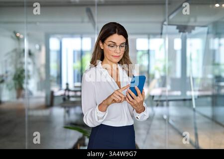 Busy business woman in her 40s working in office using mobile phone. Stock Photo