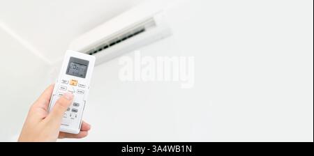 Air conditioner temperature adjustment with remote controller in room at home. Stock Photo