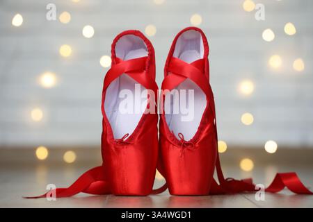 Pair of beautiful pointe shoes on floor against blurred lights. Bokeh effect Stock Photo