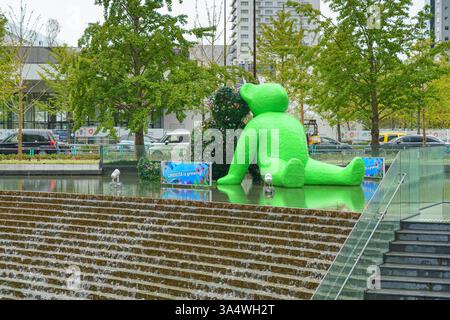 Osaka, Japan - Sep 22 2024, panoramic view of two sculptures of teddy bears sitting by the water in Umekita Plaza, one green and second from foliage o Stock Photo