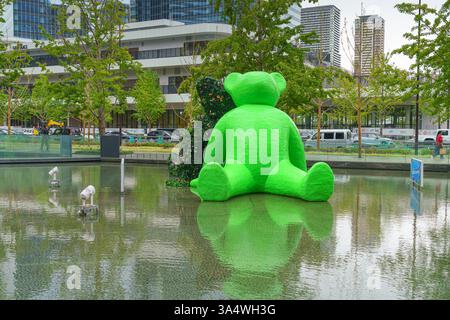 Osaka, Japan - Sep 22 2024, panoramic view of two sculptures of teddy bears sitting by the water in Umekita Plaza, one green and second from foliage o Stock Photo
