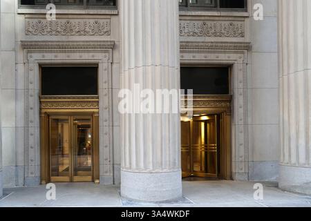 Entrance to office building with large stone columns and brass revolving doors Stock Photo