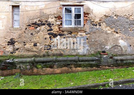 Ancient building Closeup​ pattern​ of​ surface brick​ wall​ concrete plaster​ for​ vintage​ background. Broken window and green grass. Stock Photo