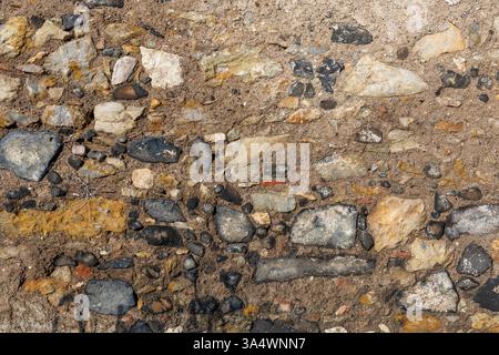 Ancient building closeup​ of​ surface brick​ wall​ concrete plaster​ of an abandoned house with broken windows black stone grey cement and ocher stone. Stock Photo