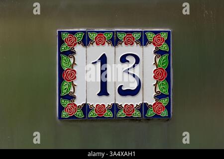 Vintage house number 13 in earthenware on the entrance of a painted wall Stock Photo