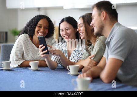 Happy interracial friends using phone in the kitchen at home Stock Photo