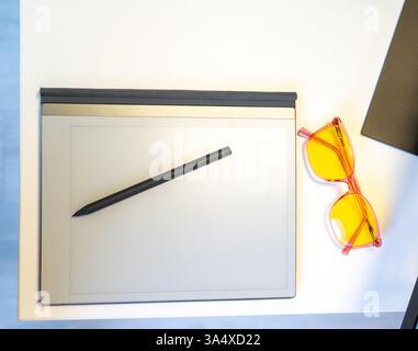 A Stylish and Modern Desk Setup Featuring a Tablet, Stylus, and Trendy Sunglasses Stock Photo