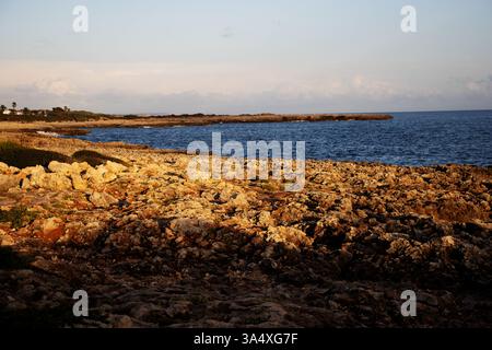 typical Menorca coast line with dark blue sea and jagged rocks with few green plants Stock Photo