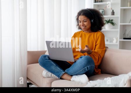 Young woman video chatting with friends in living room at home Stock Photo