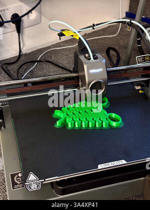 A 3D printer in action, printing a pair of green pliers. this image showcases the modern manufacturing process of 3D printing, highlighting the capabilities of this technology for creating functional objects. it reflects innovation in DIY tool creation and is ideal for showcasing the intersection of technology and craftsmanship in home workshops or small-scale production. Stock Photo