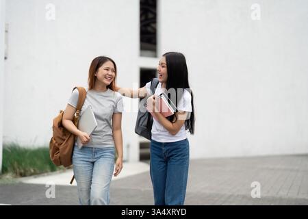 Academic Conversations and Teamwork. Two engaged students share a light-hearted moment while walking, showcasing the joy of learning together. Stock Photo