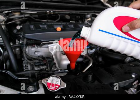 Pouring coolant liquid into a funnel of car radiator , Radiator coolant