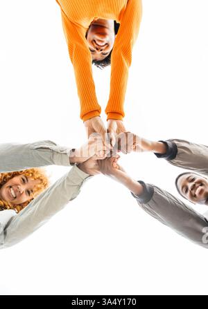 Three young people joining hands in a circle, symbolizing teamwork and collaboration Stock Photo