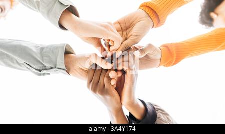 Three young people joining hands, symbolizing teamwork, collaboration, and unity in achieving shared goals Stock Photo