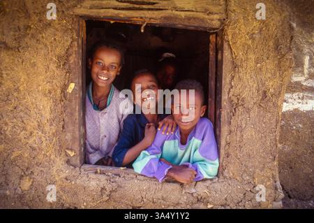 Ethiopia, Addis Abeba; family looking out of the window of an adobe  house. Stock Photo