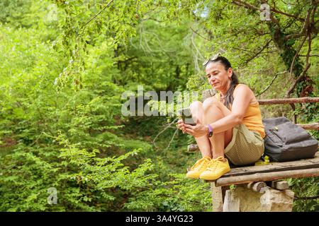 Woman using smartphone for pathfinding in forest Stock Photo