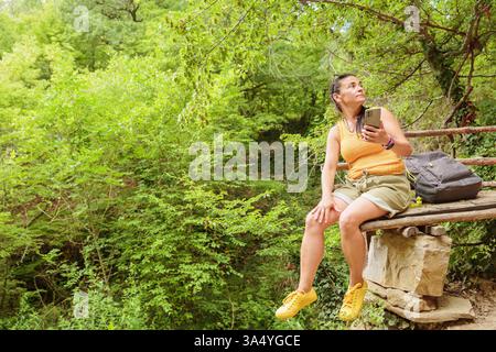 Woman using smartphone for pathfinding in forest Stock Photo