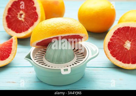 Juicer with freshly squeezed red grapefruit juice,with whole and sliced grapefruit on mint. Top view Stock Photo