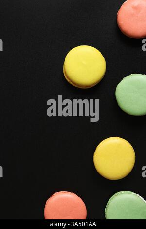 Bright French macarons on a black background, top view. Assortment of multi-colored macarons with different flavors. Delicious pastries, flat lay. Foo Stock Photo