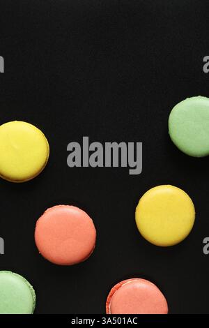 Bright French macarons on a black background, top view. Assortment of multi-colored macarons with different flavors. Delicious pastries, flat lay. Foo Stock Photo