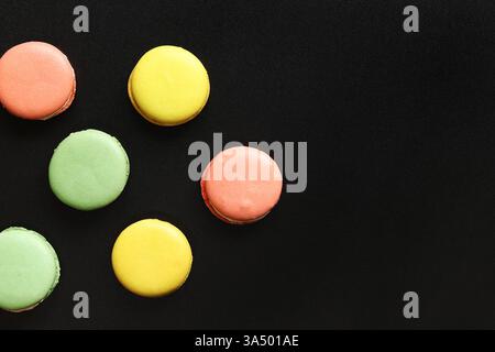Bright French macarons on a black background, top view. Assortment of multi-colored macarons with different flavors. Delicious pastries, flat lay. Foo Stock Photo