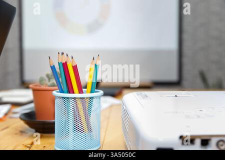 Colorful pencil in box with cactus pot on desk in office. Stock Photo