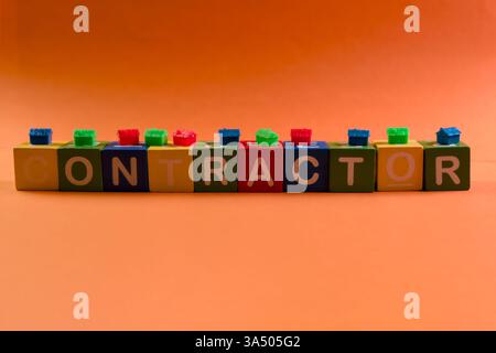 Colorful blocks spell contractor on a vibrant orange background, perfect for construction themes. Stock Photo
