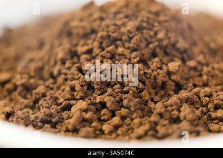 Granulated coffee grounds sit in a bowl, showcasing their rich texture, ready for brewing delicious coffee. Stock Photo