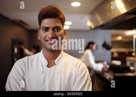 Portrait of a smiling Indian hotel restaurant chef looking at the camera. Great for culinary careers, hospitality industry and restaurant staff profiles. Stock Photo