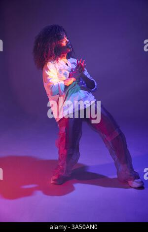 Black female dancer performing in a studio with neon lights. The energetic studio scene conveys modern dance and dynamic motion. Suitable for dance, music, and urban lifestyle campaigns. Stock Photo