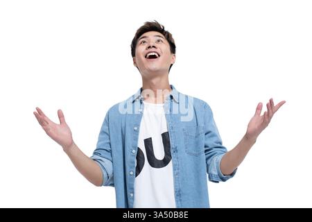 Cheerful Chinese man raises his hands and looks up in a bright studio. White background creates copy space for headlines and messaging. Perfect for positive, motivational themes, corporate wellness, and lifestyle visuals. Stock Photo