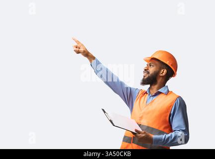 Black architect standing in a studio setting, gesturing with a finger while holding a project folder. Clean white background emphasizes construction and architectural planning concepts. Useful for builder, construction management, or architectural design visuals. Stock Photo