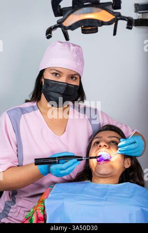 Professional female dentist using laser whitening on a patient in a modern dental clinic. The scene captures cosmetic dentistry in action with chairside procedures and dental tools. Perfect for healthcare marketing, dental care promotions, and clinic advertising. Stock Photo