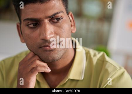 Portrait of a pensive UX designer contemplating design changes after a review. The focused expression and UI context support technology, product development and collaboration themes. Stock Photo