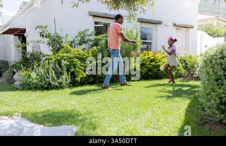 Easter Egg hunt, Father and daughter playing catch with ball in sunny backyard garden Stock Photo