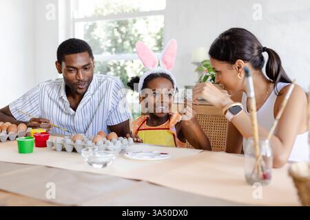 Family painting Easter eggs together, smiling and enjoying creative holiday activity Stock Photo
