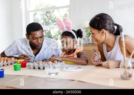 Family painting Easter eggs together, enjoying creative time at home Stock Photo