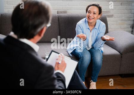 A psychologist conducts a therapy session with a patient in a studio setting. The calm, professional environment highlights counseling and mental health care. Stock Photo