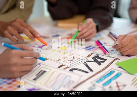 Close up view of a young Asian UX UI designer discussing a project in a meeting room. A professional scene highlighting teamwork, design, and collaboration in an office setting with a laptop and prototype. Stock Photo