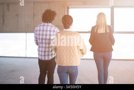 Cheerful young startup team carries boxes through a sunlit office during a move into a new space. This image captures teamwork, optimism and the momentum of a growing company. Stock Photo