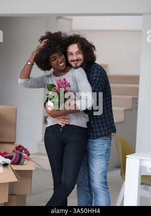 Happy multiethnic couple moving into a new home, unpacking boxes and settling in. The scene conveys relocation, home improvement, and togetherness. Suitable for real estate, lifestyle, and family moving themes. Stock Photo