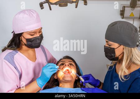 Top-down view of a dental team attending to a patient during a routine checkup with dental tools and equipment on display. Suitable for healthcare and dental clinic themes. Stock Photo