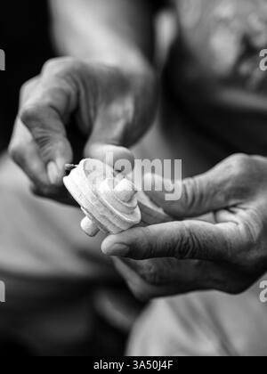 Monochrome image of a male artisan in a workshop, repairing a stringed instrument with no faces visible. The scene emphasizes traditional craftsmanship, shop life, and handmade music goods. Suitable for features on luthiers, instrument making, and small business. Stock Photo