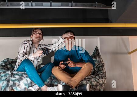 Two colleagues during a break in a creative startup office, playing computer games together. The relaxed competition captures teamwork, leisure and technology in a modern workspace. Great for content about startup culture, office life and work-life balance. Stock Photo