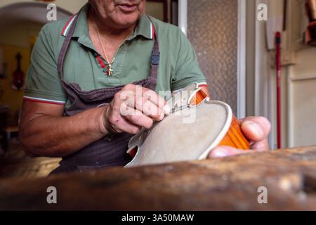 Violin maker at work in an Italian workshop. Close-up shows craftsmanship, tools and timber, ideal for music, craft and artisanal business contexts. Great for features about luthiers, heritage instruments and Cremona style violin making. Stock Photo