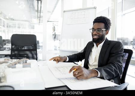 Smiling dark-skinned businessman in a modern office. This confident professional portrait showcases leadership, business success, and office life. Stock Photo