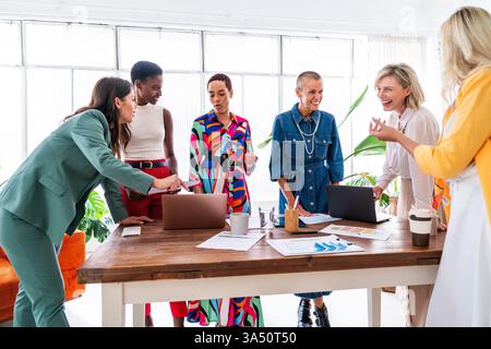 Group of confident diverse businesswomen meeting in a modern office. A multiethnic team brainstorms and collaborates on a project, showcasing leadership and teamwork. Ideal for corporate communications, women in business, and workplace visuals. Stock Photo